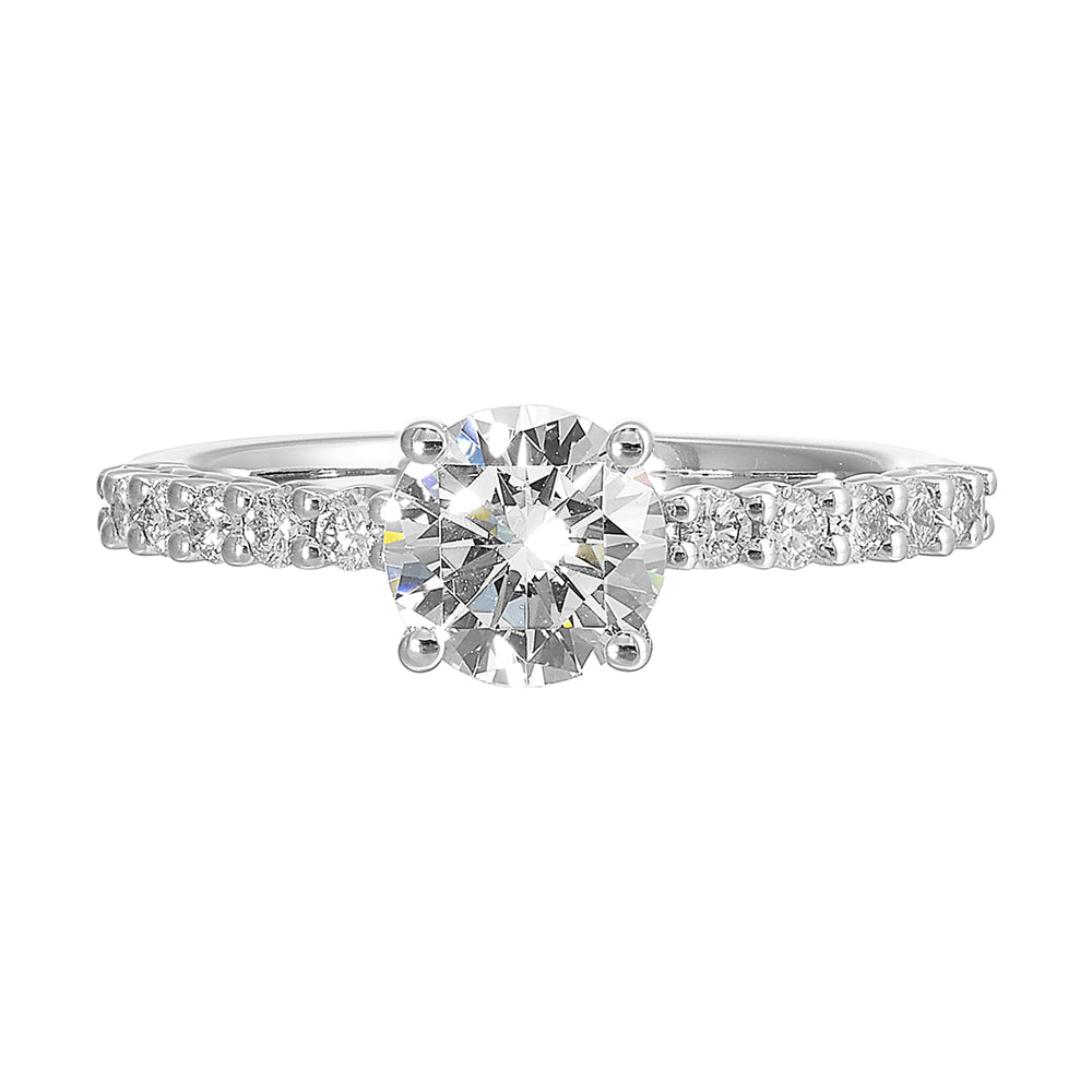 A dazzling round solitaire takes center stage, held by a sleek shank adorned with sparkling diamonds is a perfect choice for any occasion.