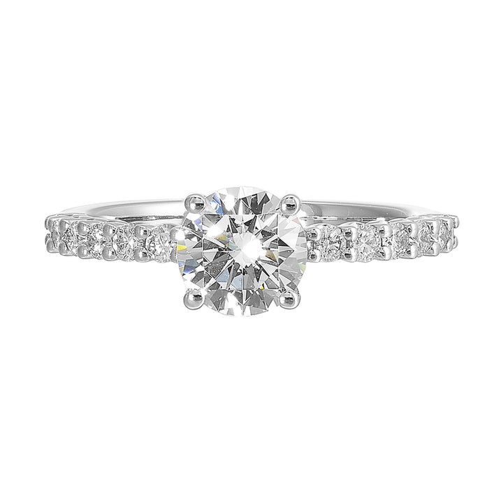 A dazzling round solitaire takes center stage, held by a sleek shank adorned with sparkling diamonds is a perfect choice for any occasion.