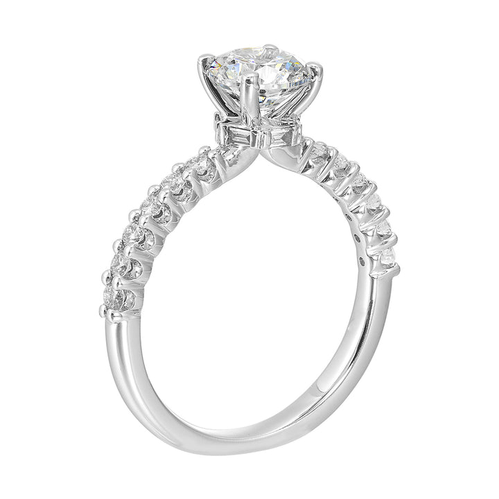 A dazzling round solitaire takes center stage, held by a sleek shank adorned with sparkling diamonds is a perfect choice for any occasion.