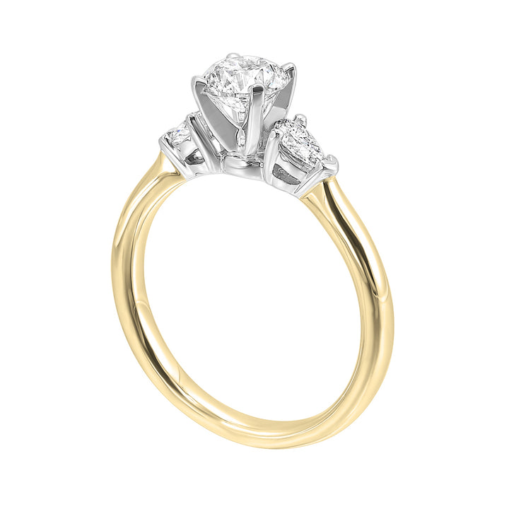 Stunning engagement ring features a round brilliant cut diamond in the center of a three stone setting, adorned on either side by a smaller pear diamond set on the tapered shank.