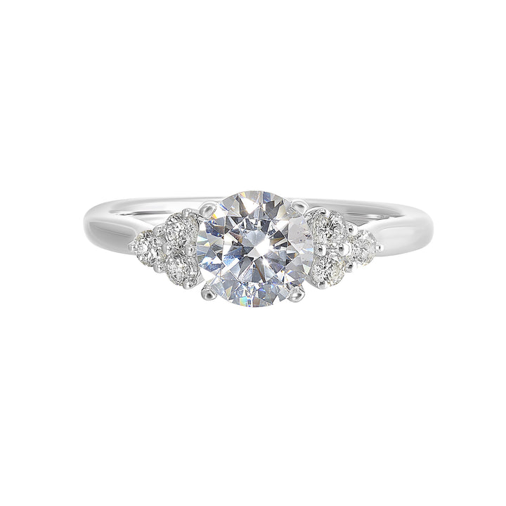 Three stone ring features a trinity of diamonds on either side, focusing the round solitaire at center, is a symbol of everlasting love.