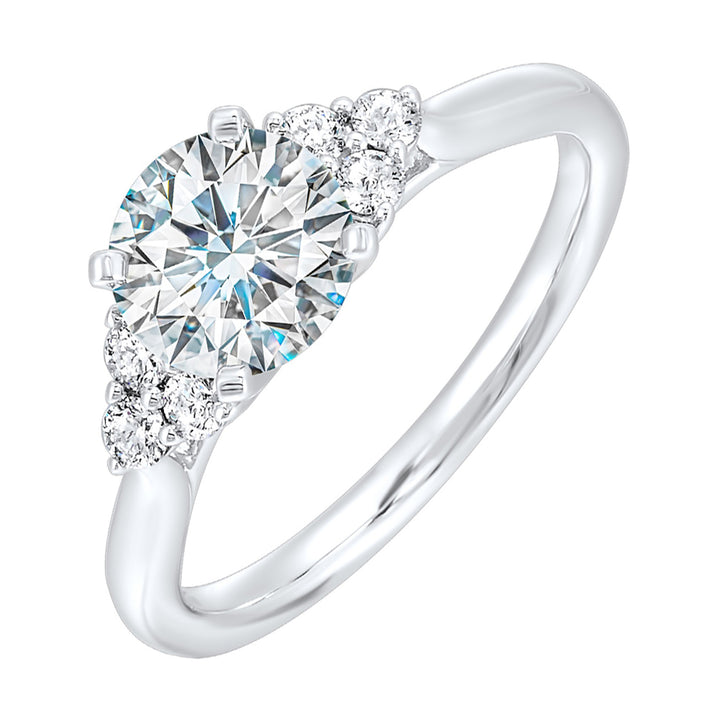 Three stone ring features a trinity of diamonds on either side, focusing the round solitaire at center, is a symbol of everlasting love.