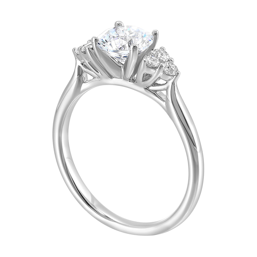 Three stone ring features a trinity of diamonds on either side, focusing the round solitaire at center, is a symbol of everlasting love.