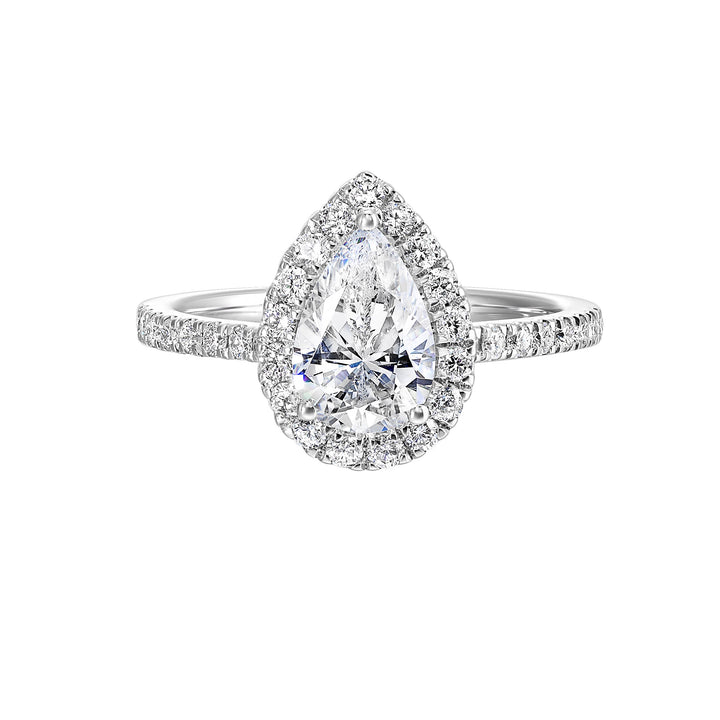 The pear cut solitare shines in this elegant ring, embraced by a delicate halo. The diamond shank adds a touch of sparkle, showcasing the beauty of the pear and halo at its finest.