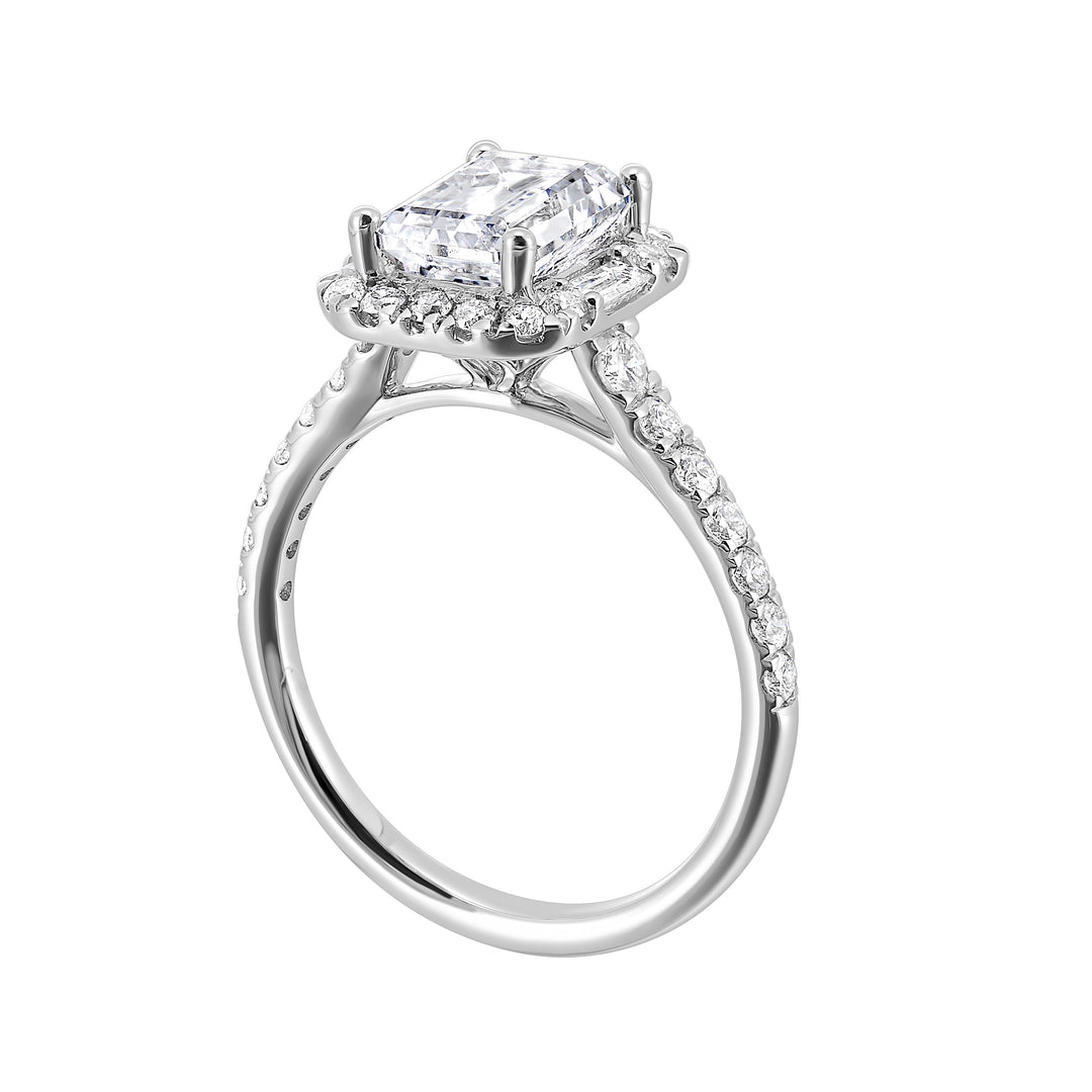 A glittering softened halo of diamonds surrounds the center emerald with adjacent baugettes on both the sides. Pave split shank adds a stylish, dazzling look.
