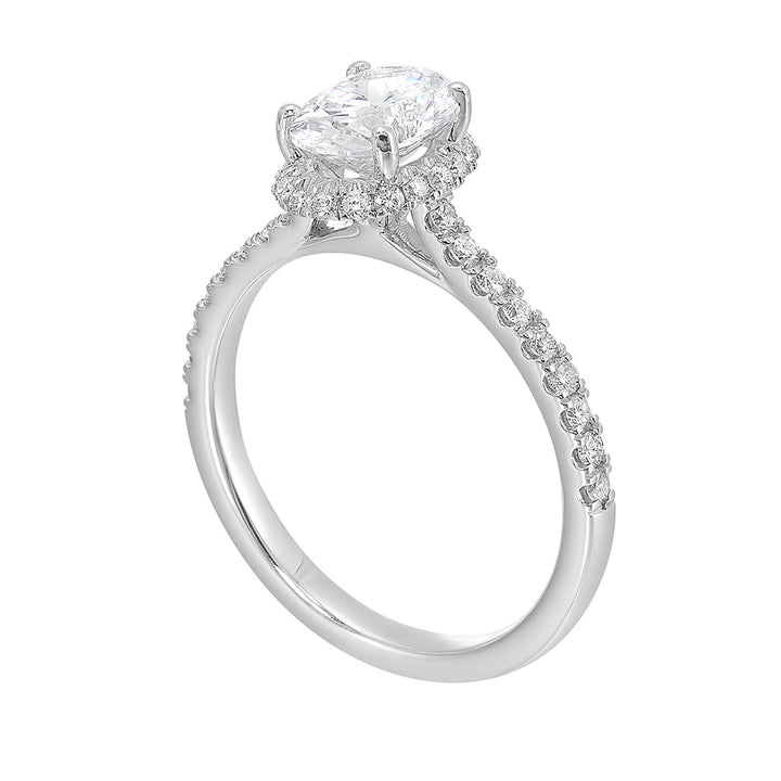 This stunning engagement ring features an oval solitare diamond, accented by pave set round diamonds on shank and a hidden halo.
