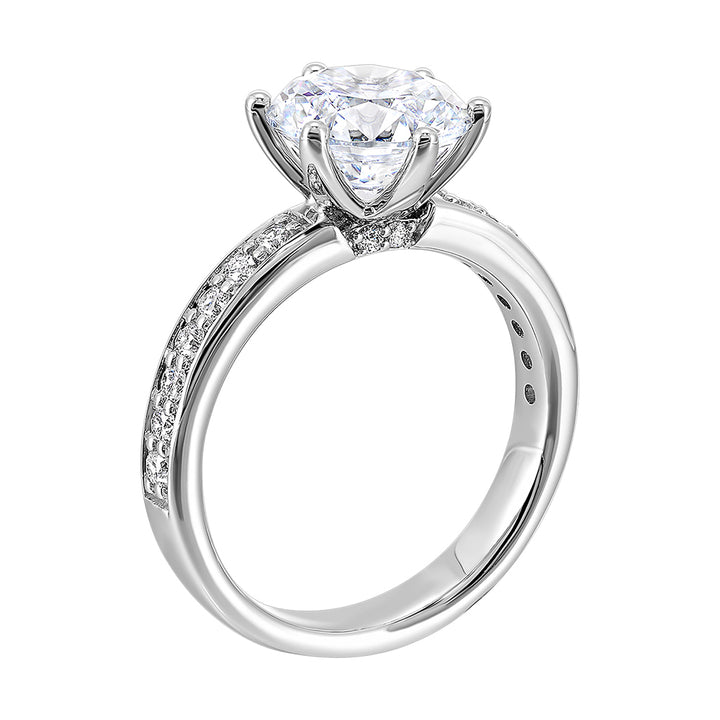A six prong setting secures round solitare diamond with pave of diamonds in shank is perfect for the classic look.
